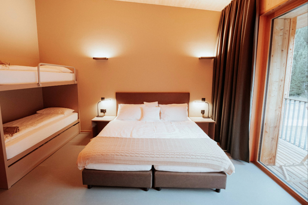 Camera Family del Campra Lodge con letto matrimoniale, spazi ampi, balcone panoramico e comfort ideale per famiglie e piccoli gruppi immersi nella natura alpina