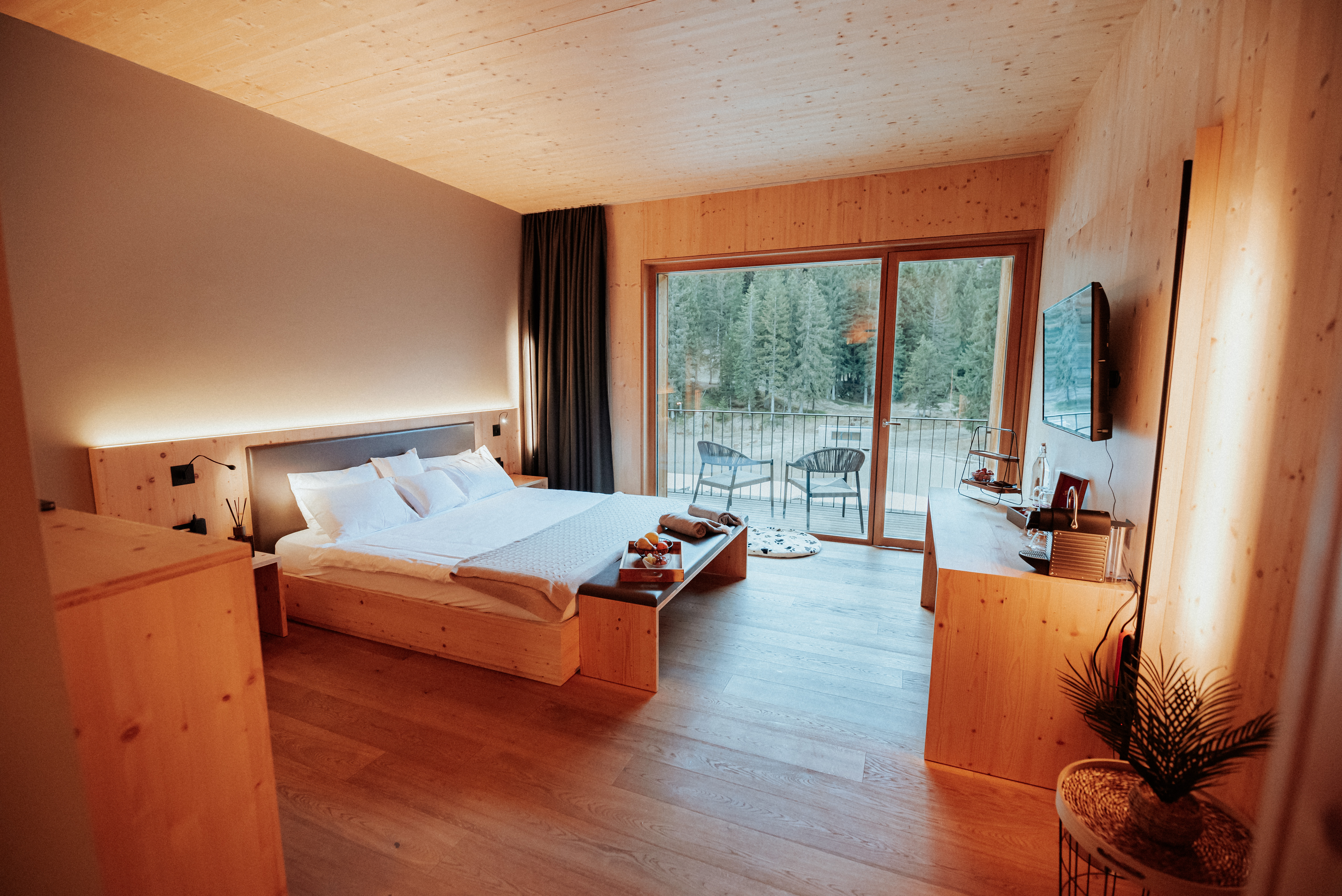 Camera Comfort del Campra Lodge con letto matrimoniale, arredi in legno naturale, balcone panoramico e vista sul bosco alpino